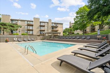 A pool surrounded by lounge chairs and trees.